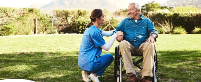 Caregivers like this one talking to a smiling senior patiently and compassionately help clients and help them with aging in place while dealing with different conditions.