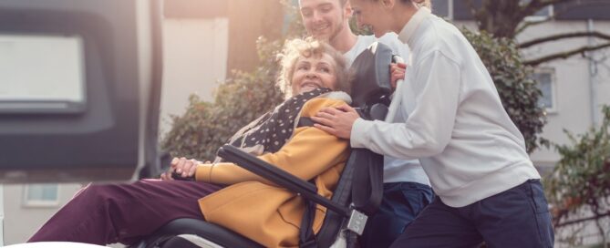 2 caregivers help an older adult get into a vehicle using a ramp, showing how equipment is valuable to professional caregivers when helping older adults.