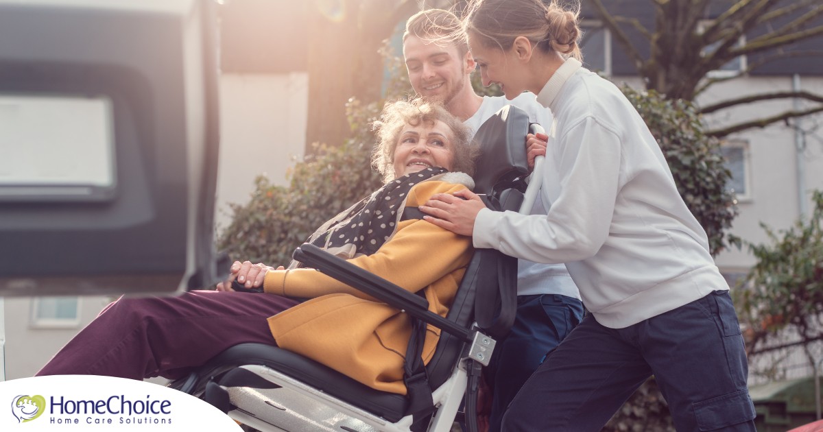 2 caregivers help an older adult get into a vehicle using a ramp, showing how equipment is valuable to professional caregivers when helping older adults.