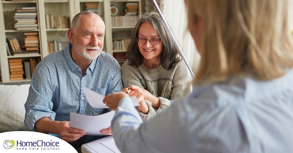 An older couple receives and considers papers from a woman, representing someone considering long-term care insurance.