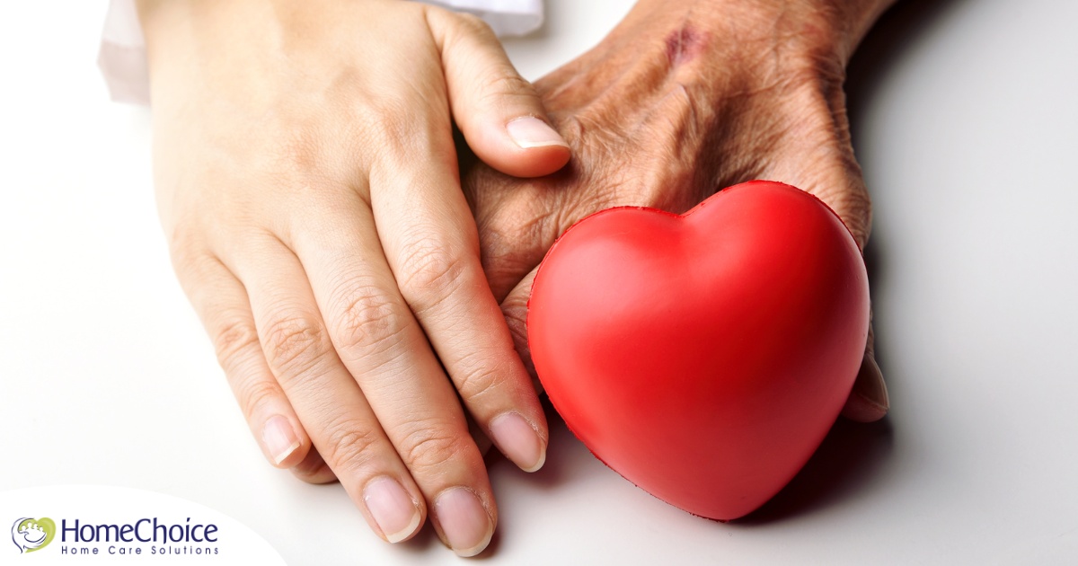 An old hand and a young hand with a heart represent caregiving.