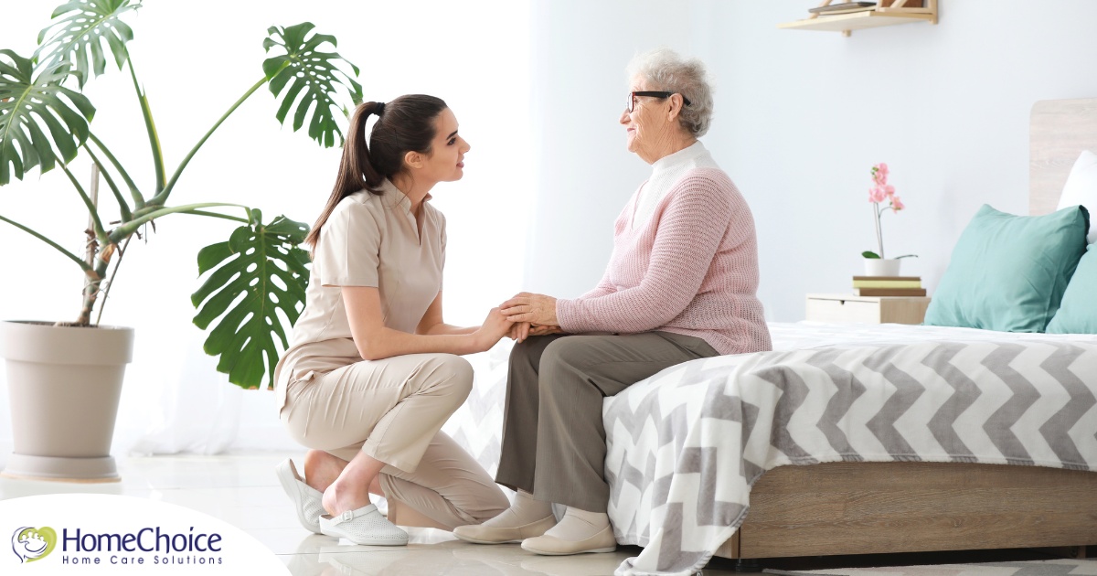 Communicating as a caregiver involves patiently and compassionately listening, as this caregiver is doing with her senior client.