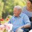 A caregiver takes a senior outside to visit a garden, highlighting one idea for senior activities.