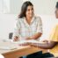 A woman happily interviews another woman, representing how well caregiver interviews can go when prepared.